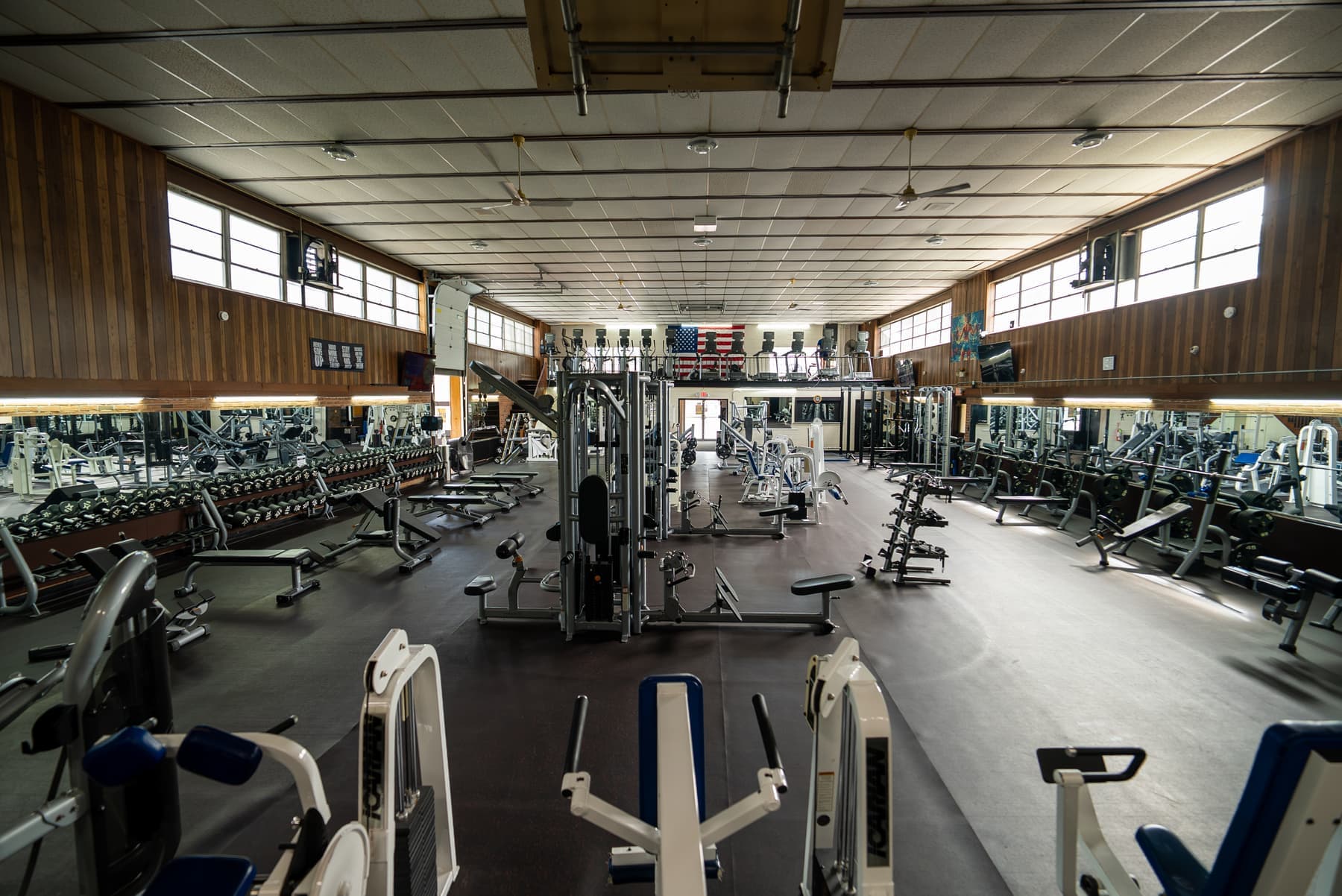 Personal training on the Greater Gym main floor with dumbbells and plate-loaded machines