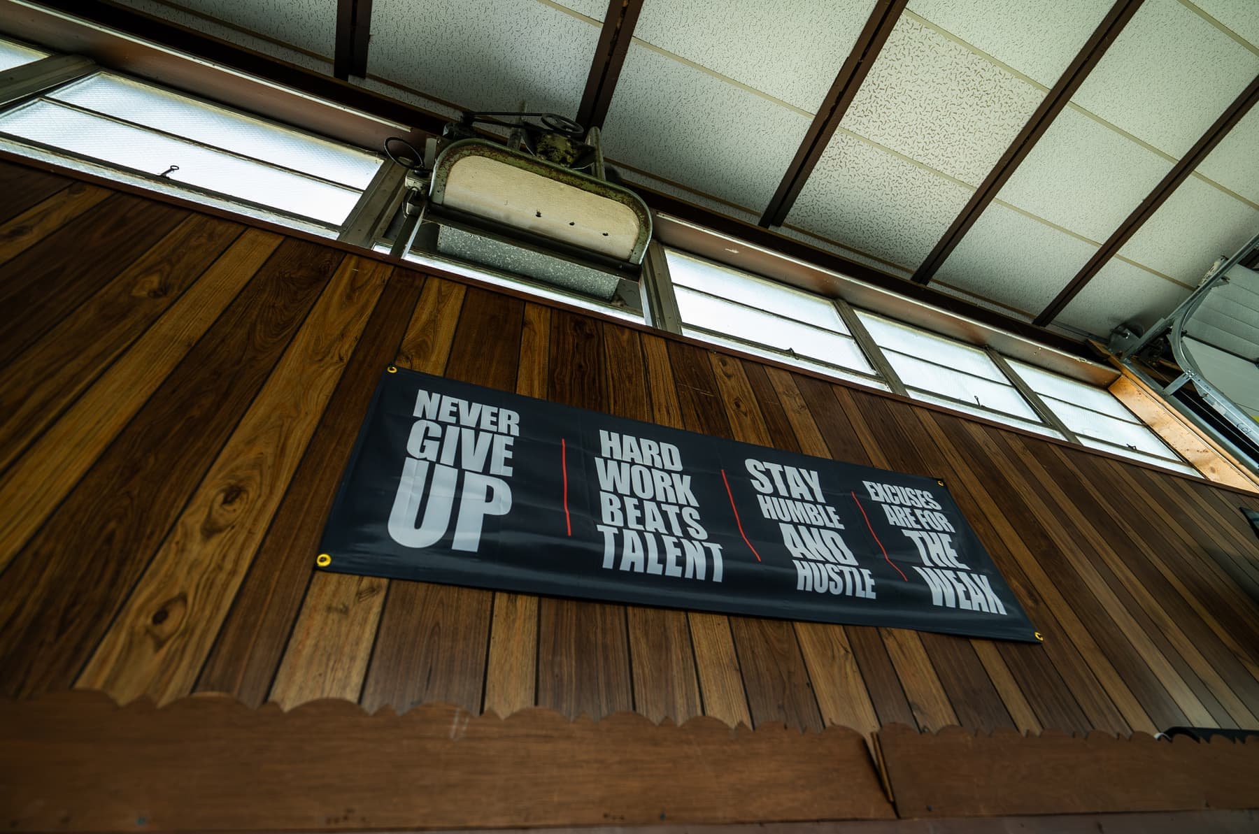 Never give up - hard work beats talent banner on the wood wall at Greater Gym